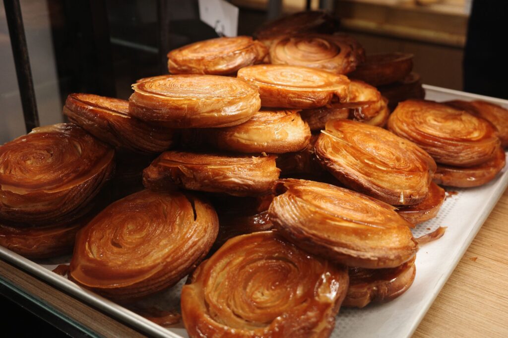A closeup of freshly-baked Kouign-amann on a tray on the table