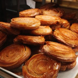A closeup of freshly-baked Kouign-amann on a tray on the table